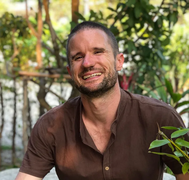 Anthony Biddlecombe smiling outdoors among green plants