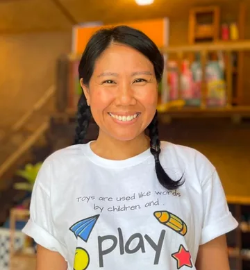 Jeerawan Panma smiling in a white play t-shirt in a classroom